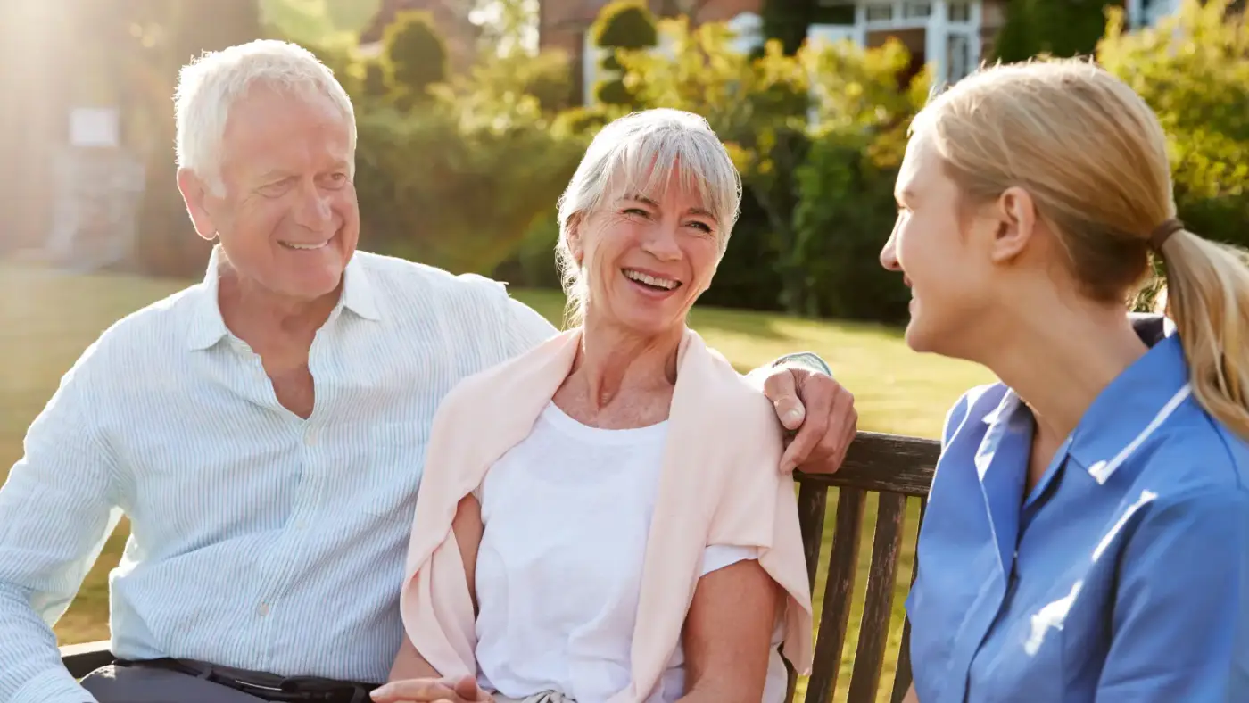 husband and wife on bench with carer