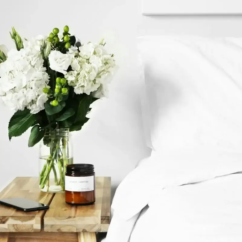 flowers next to bed with white sheets
