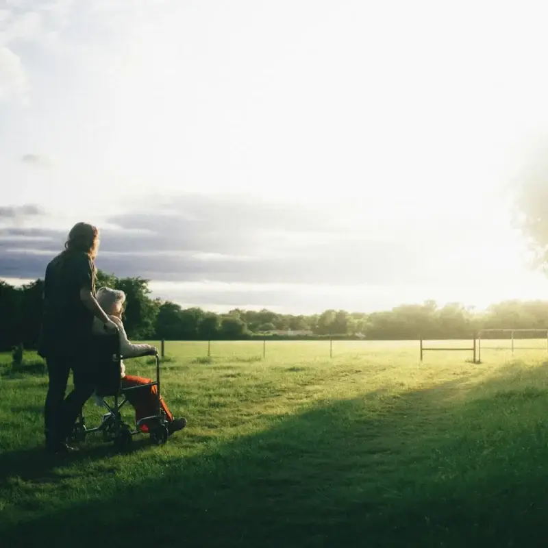 woman standing next to woman riding wheelchair